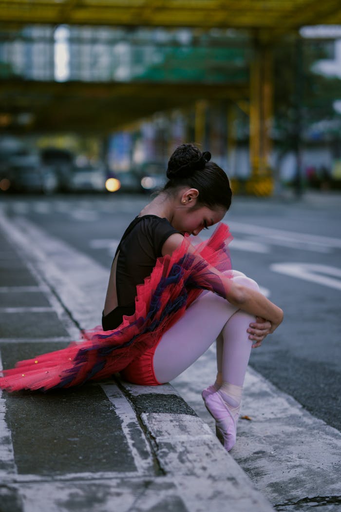 Ballet dancer in striking pose on an urban street, showcasing art and grace.